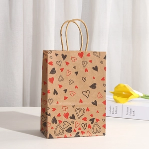 Close-up of heart print kraft paper gift bag with sturdy handles on a white background