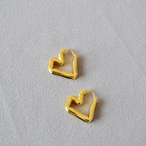 Close-up of golden geometric heart-shaped brass earrings with minimalist folded metal design