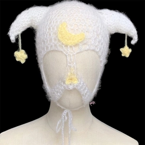 Detail of white crochet knit devil horn hat featuring moon and star hanging charms