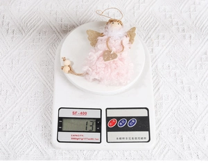Mesure du poids de l'ange de Noël en peluche rose affichant 13g sur une balance