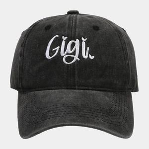 Dettaglio del ricamo bianco Gigi su un berretto da baseball in denim nero lavato e vissuto