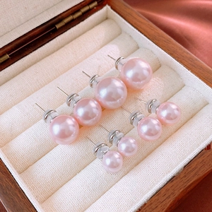 Set of round pink pearl stud earrings in various sizes displayed in a wooden jewelry box