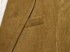 Detail of brown corduroy fabric texture and side pocket on a casual loose blazer