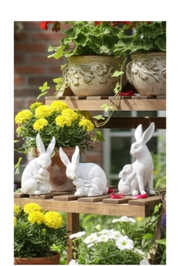 Vue détaillée de trois statuettes de lapins blancs en résine sur un support en bois
