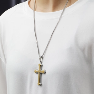 Close-up of a stainless steel cross pendant with engraved Lord's Prayer on a silver chain
