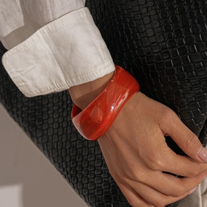 Close-up of wide amber red acrylic bangle with unique marbled texture on wrist