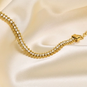 Close-up of a three-row gold bracelet with sparkling cubic zirconia on champagne silk