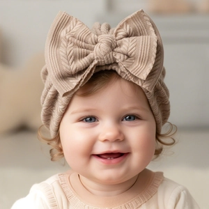 Close-up of a baby wearing a khaki chunky knit headband with a large 3D bow detail