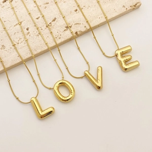 Detail of four gold puffy 3D letter pendants spelling LOVE on beaded snake chains