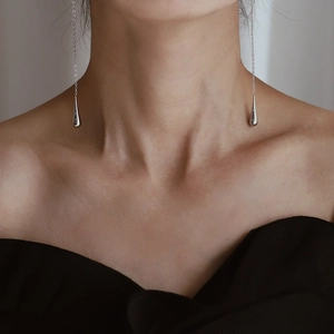 Close-up of long silver water drop tassel earring worn by model showing elegant drape