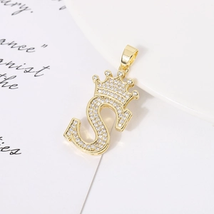 Detail of gold-plated crown and S-letter pendant with shimmering cubic zirconia inlay