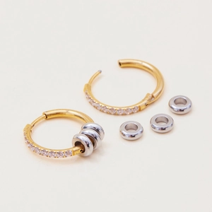 Detail of 18K gold-plated earrings with silver rings and white zircon stones on beige base