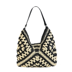 Handwoven straw tote bag with black and white geometric patterns and leather strap
