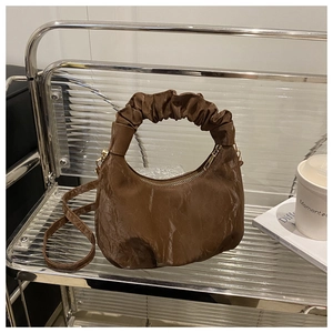 Makro-Detail der dunkelbraunen Faltenstruktur und des Griffs einer minimalistischen Tasche