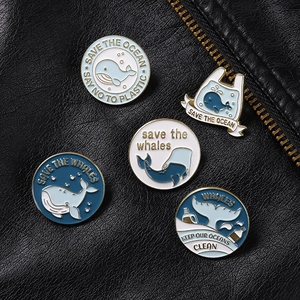 Set of five ocean conservation enamel pins with whale motifs on black leather jacket