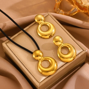 Detailed shot of golden geometric teardrop jewelry set on elegant beige silk background
