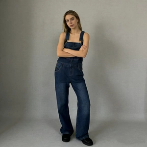 Front view of woman wearing casual dark blue denim overalls with pocket details