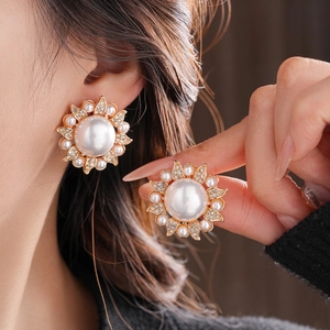 Luxe flower pearl earrings with sparkling rhinestones and gold metal petals on a model