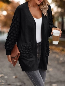 Women's black V-neck knit cardigan with textured sleeves and pockets in outdoor street style