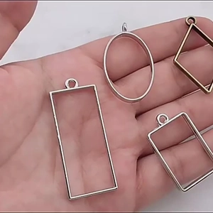 Hand holding assorted geometric alloy open bezels in silver and antique bronze colors
