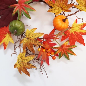 Detail of autumn candle ring with colorful maple leaves, mini pumpkins, and red berries