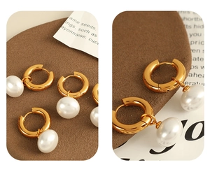 Detailed view of gold hoop earrings with pearl pendants on a textured brown background