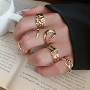 Set of five gold geometric rings with irregular textures shown on model hand