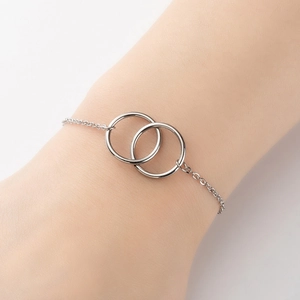 Elegant silver interlocking double ring bracelet for women on wrist in minimalist style