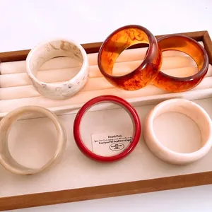 Minimalist resin round bangles in marble and amber colors displayed on a jewelry tray