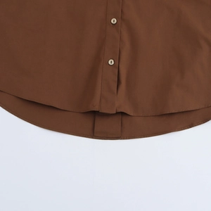 Detail view of brown poplin shirt featuring curved hemline and buttoned placket details