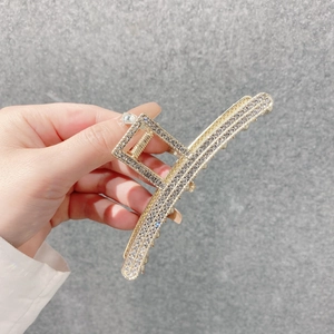 Détail d'une grande pince à cheveux en métal doré ornée de strass étincelants