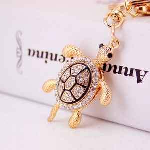 Porte-clés tortue avec placage d'or, strass brillants et émail noir sur un livre blanc