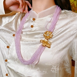 Detail of purple multi-layer beaded necklace with gold butterfly pendant on a model