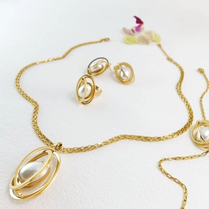 Flat lay of elegant gold jewelry set with oval imitation pearls and lavender accents