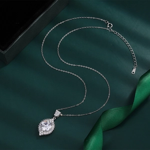 Close-up of teardrop zirconia necklace pendant with silver plating on green background