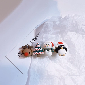 Macro view of Christmas hair clip featuring cute reindeer, tree, snowman and penguin decor