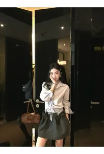 Dettaglio di minigonna in lana grigia con camicia bianca a maniche lunghe con coulisse
