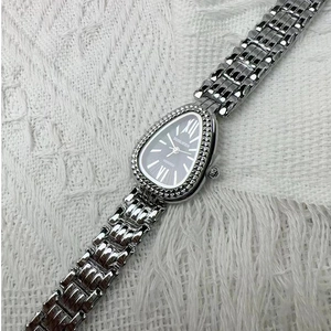 Silver teardrop quartz watch with black dial and metal chain strap on fabric background