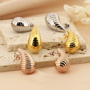 Macro view of gold, silver, and rose gold hollow teardrop earrings with spiral texture