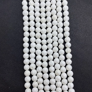 Macro-opname van 5x8mm witte natuurlijke schelpkralen met gedetailleerde roosgravures voor sieraden