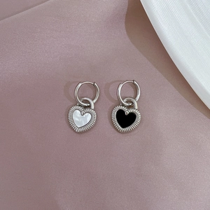 Detail of silver heart hoop earrings featuring white shell and black enamel inlays