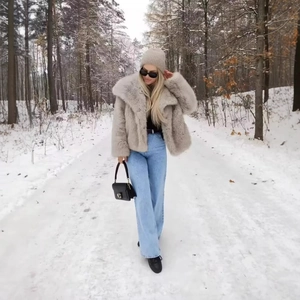 Veste moelleuse en fausse fourrure beige pour femme avec jean dans une forêt enneigée