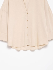 Détail d'une chemise en coton lin beige avec fermeture à boutons et texture tissée
