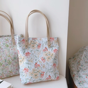 Detail of floral canvas tote bag with reinforced faux leather straps and metal rivets