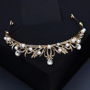 Golden bridal crown with white pearls and sparkling teardrop rhinestones on black stand