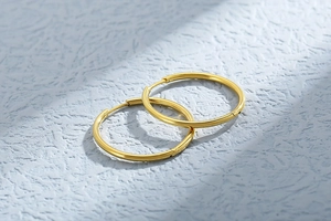Macro detail of polished gold hoop earrings with a smooth metallic texture