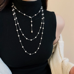Gros plan d'un collier multicouche en argent avec perles blanches et pendentif goutte