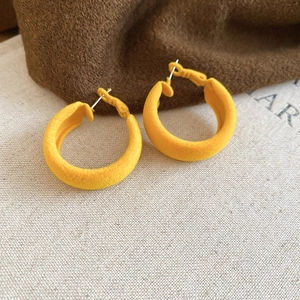 Détail de créoles en C floquées jaunes avec une texture velours mate douce sur tissu