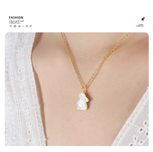 Détail du collier de lapin doré avec pendentif nacré sur le cou du mannequin