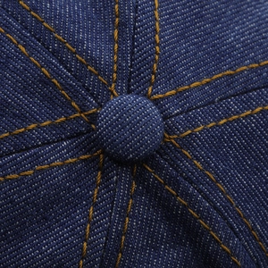 Détail macro de la couronne en denim bleu foncé avec coutures orange contrastées